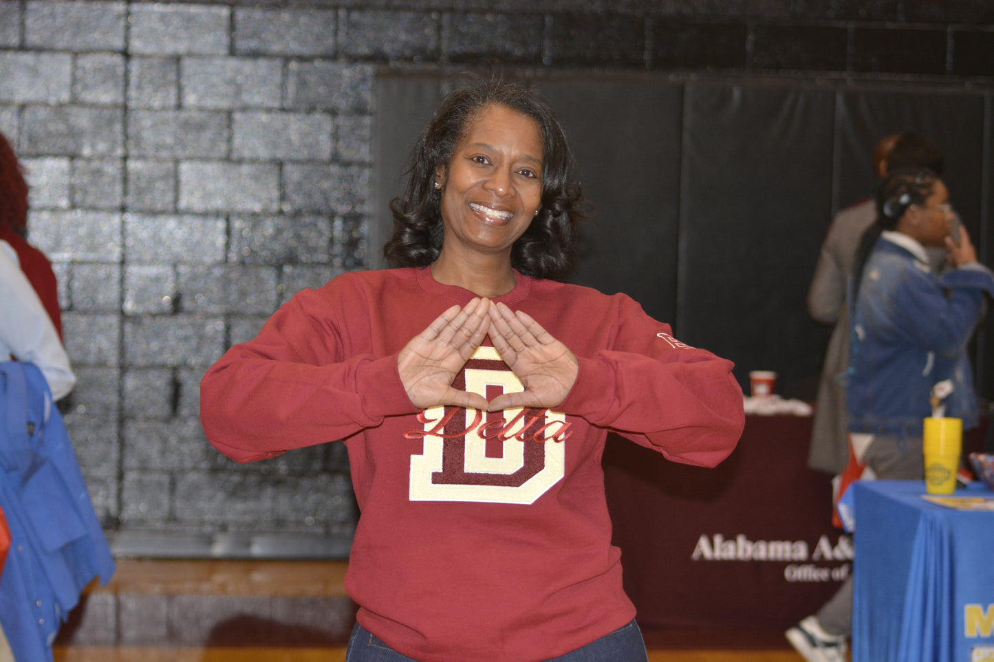 Woman wearing Delta Sigma Theta crimson crewneck sweatshirt with chenille D and embroidered Delta script